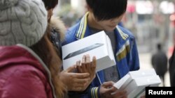 People holding newly-purchased iPad minis wait outside an Apple Store during the China launch for the product, in Shanghai, December 7, 2012. 