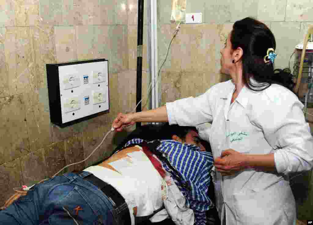 A Syrian doctor treats an injured man who was wounded at the open-air cafeteria at Damascus University in the central Baramkeh district, March 28, 2013.