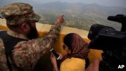 FILE - A Pakistani army officer points out the Indian forward-area posts to journalists at Bagsar post on the Line of Control that divides Kashmir between Pakistan and India, Oct. 1, 2016. The two countries have fought two wars over the disputed Himalayan region.