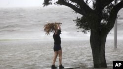 A woman stands on a partially submerged picnic bench in the storm surge from Isaac, on Lakeshore Drive along Lake Pontchartrain, as the storm approaches landfall, in New Orleans, Aug. 28, 2012. 