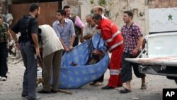 Photo released by the Syrian official news agency SANA, Syrian men carry a dead body at the scene where triple bombs exploded at the Saadallah al-Jabri square, in Aleppo, Syria, October 3, 2012.