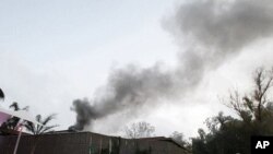 Foreign journalists gather outside of Rixos hotel as plume of smoke rises in the sky in Tripoli, Libya, June 9, 2011