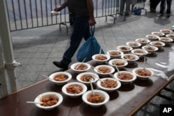 Seorang pria berjalan melewati masakan yang terbuat "limbah" makanan yang dianggap tak layak oleh toko bahan pangan karena tampilannya dalam sebuah festival untuk menentang perilaku membuang-buang makanan di Athena, Yunani, 11 Oktober 2015
