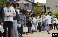 Residents queue up for drinking water at an elementary school in Takatsuki, Osaka, June 18, 2018, after a strong quake hit the area during the morning rush hour.