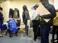 Polling site officials, left, check on a voting scanner after it jammed, forcing voters to manually file their ballots until a repair was made, Nov. 6, 2018, in the Parkchester community of the Bronx borough of New York.