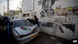 Palestinians look at a car used in an attempted ramming attack on Israeli soldiers in the Qalandia refugee camp on the outskirts of the West Bank city of Ramallah, Dec. 16, 2015. 