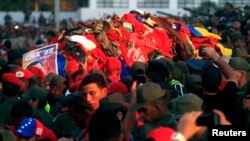 El ataúd del expresidente Hugo Chávez cubierto de ropa lanzada por la gente en las calles de Caracas. sus restos podrían ir al Panteón Nacional.