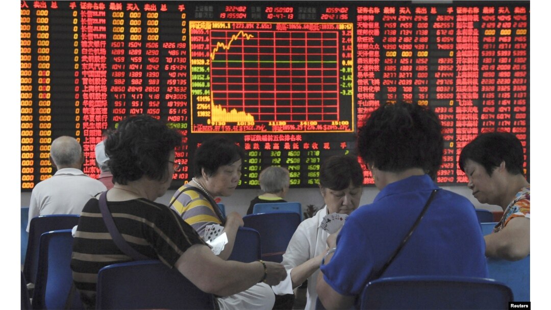 Investors play cards in front of an electronic board showing stock information at a brokerage house in Shanghai, China, Sept. 9, 2015.