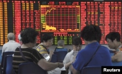 Investors play cards in front of an electronic board showing stock information at a brokerage house in Shanghai, China, Sept. 9, 2015.