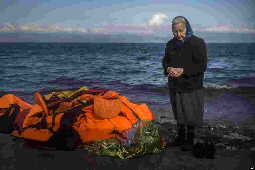 Seorang perempuan lanjut usia berdiri di pantai pulau Yunani, Lesbos, di samping tumpukan jaket pelampung, setelah para pengungsi dan migran tiba dari pesisir Turki. Para pemimpin Uni Eropa pada hari Kamis (17/12) menetapkan waktu selama enam bulan untuk memutuskan apakah akan melanjutkan rencana pembentukan badan penjaga perbatasan yang bisa dikerahkan ke negara-negara yang tidak mampu atau tidak mau mengatur perbatasan mereka sementara ribuan pengungsi terus tiba di Eropa setiap harinya.