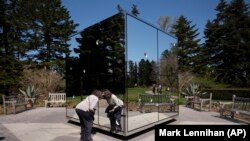 A woman peers into the sculpture "Infiniti Mirrored Room - Illusion Inside the Heart" by Japanese artist Yayoi Kusama at the New York Botanical Garden, Thursday, April 8, 2021 in the Bronx borough of New York.