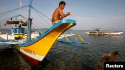 资料照片: 2012年5月10日菲律宾渔民坐在抵达斯卡伯勒浅滩(中国称黄岩岛、菲律宾称巴约的马辛洛克)的船上