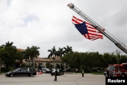 FILE - A hearse carrying the casket of Aaron Feis, one of the victims of the mass shooting at Marjory Stoneman Douglas High School, drives past a U.S. flag, placed on a firetruck, during his funeral in Coral Springs, Fla., Feb. 22, 2018.