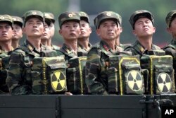 FILE - In this July 27, 2013, file photo, North Korean soldiers carrying packs marked with the nuclear symbol turn and look towards leader Kim Jong Un during a military parade in Pyongyang, North Korea.