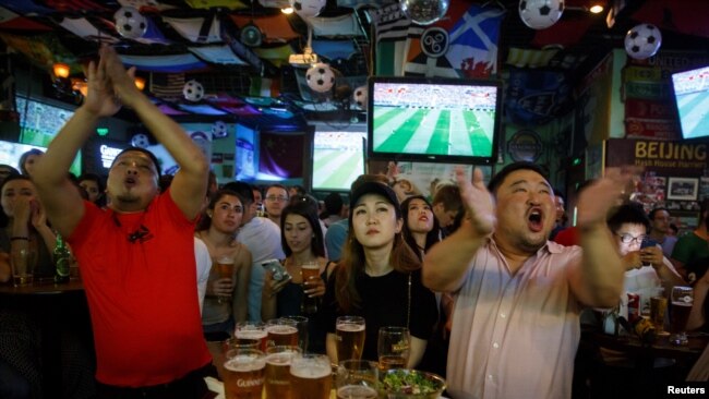 2018年6月14日,人们在北京的一家酒吧观看世界杯甲组俄罗斯对沙特阿拉伯足球比赛,他们看得很投入,聚精会神。