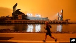 FILE - In this Wednesday, Sept. 9, 2020 file photo, a jogger runs along McCovey Cove outside Oracle Park in San Francisco, under darkened skies from wildfire smoke. (AP Photo/Tony Avelar)