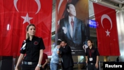 Men greet each other in front of Turkish flag and picture of modern Turkey's founder Mustafa Kemal Ataturk at Istanbul Ataturk airport, Turkey, following yesterday's blast, June 29, 2016. 