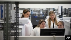 FILE - Lab technicians work at the Brazilian Doping Control Laboratory before a visit by Brazil's sports minister in Rio de Janeiro, Brazil, May 8, 2015.