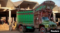Workers unload fruit from a decorated truck at the wholesale produce market in Faisalabad, Pakistan, May 4, 2017.