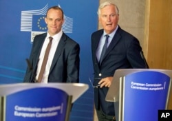 FILE - Britain's Secretary of State for Exiting the European Union Dominic Raab, left, and EU chief Brexit negotiator Michel Barnier arrive for a press conference at EU headquarters in Brussels, Aug. 21, 2018.