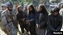 Taliban militants, right, who were arrested by Afghan border police, stand during a presentation of seized weapons and equipment, Jalalabad, Dec. 29, 2015.