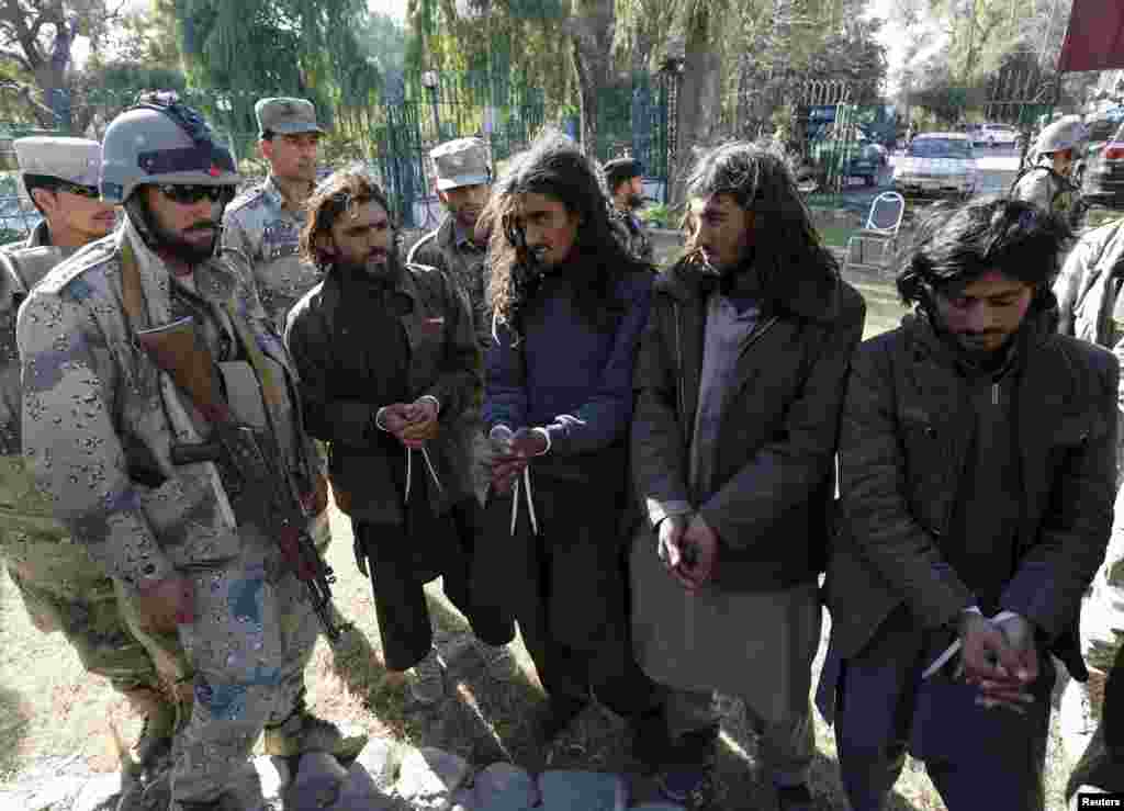 Những kẻ chủ chiến Taliban (phải), bị cảnh sát biên giới Afghanistan bắt, đứng trình diện trước giới truyền thông cùng các loại vũ khí và thiết bị bị tịch thu, ở thành phố Jalalabad, Afghanistan.