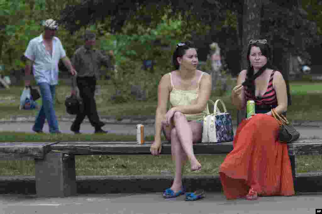 Para perempuan menikmati udara hangat di alun-alun pusat kota Slovyansk, Ukraina timur (19/5).&nbsp;(AP/Alexander Zemlianichenko)