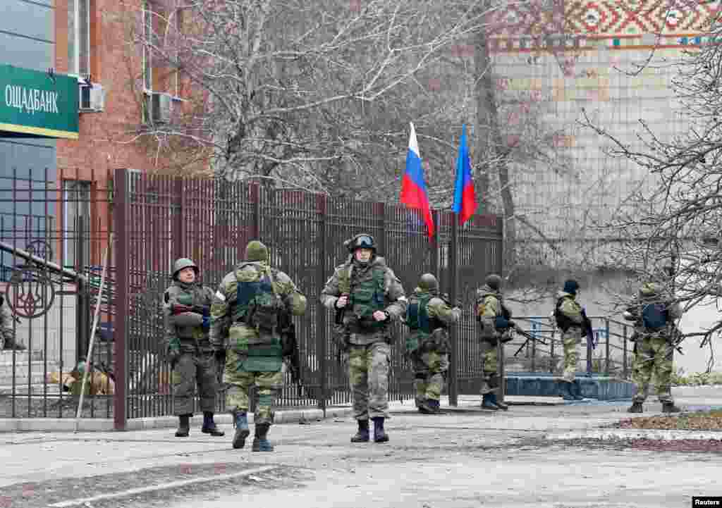 Servicemen of pro-Russian militia stand guard outside the Oschad bank branch in Stanytsia Luhanska in the Luhansk region, Ukraine, Feb. 27, 2022.