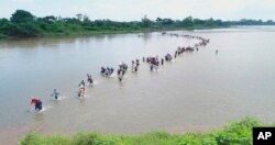 FILE - Salvadoran migrants cross the Suchiate River near Tecun Uman, Guatemala, the border with Mexico, Nov. 2, 2018, as the caravan of Central American migrants make its way north, hoping to enter the United States.