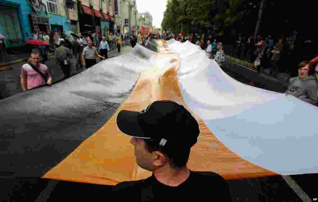 Activists hold a huge Russian Empire flag during an anti-government protest in Moscow June 12, 2012. Thousands of Russians said they would defy Kremlin pressure and attend a march in Moscow on Tuesday to protest against President Vladimir Putin, shrugging