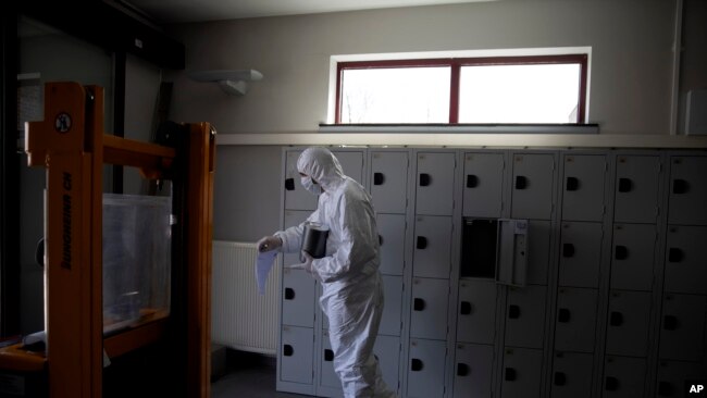 Un trabajador con equipo de protección lleva una urna de cenizas de un fallecido por la Covid-19, en el crematorio y centro funerario de Pontes en Wilrijk, Bélgica, el viernes 3 de abril de 2020. En el crematorio de Wilrijk, cerca de Amberes, se han hecho 200 cremaciones adicionales debido a la enfermedad del nuevo coronavirus desde el comienzo de la semana.