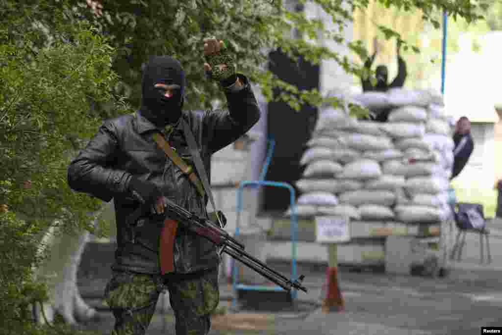 A pro-Russian armed man waves to participants of an International Worker's Day parade in the town of Slovyansk, May 1, 2014.