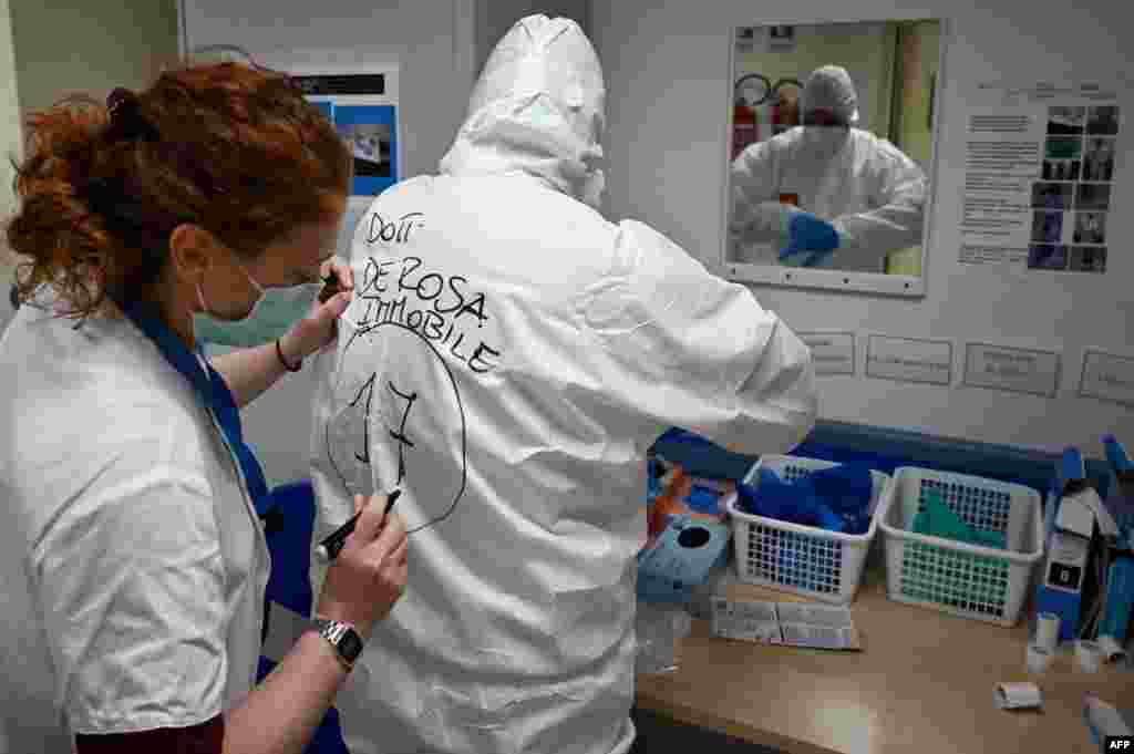 A nurse writes the name of Italian anaesthesiologist Doctor Marino De Rosa on the back of his Personal Protective Equipment (PPE) at the ICU division of the Covid unit at the San Filippo Neri hospital, in Rome, Italy, April 29, 2020.