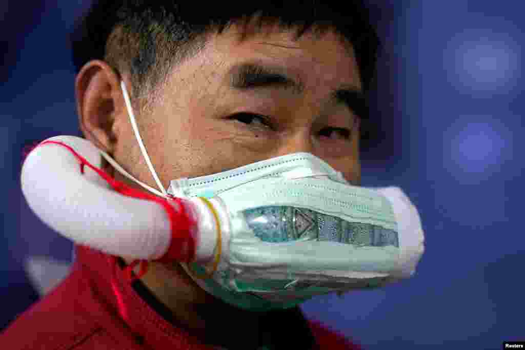 مرد چینی با ماسک مخصوص دست ساختش در شهر ووهان، منشای همه&zwnj;گیری کووید۱۹