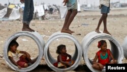 FILE - Children sitting inside cement water pipes play on the Marina beach in the southern Indian city of Chennai, Oct. 10, 2013. 