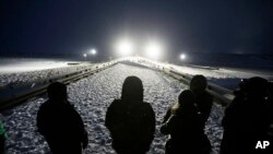  Military veterans stand on a bridge across from police protecting the Dakota Access oil pipeline site in Cannon Ball, N.D., Dec. 1, 2016.