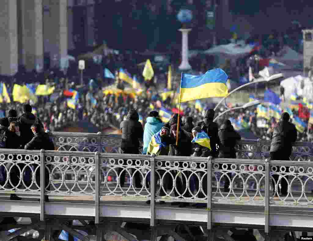 A man carrying a Ukrainian flag gestures as he stands on top of a bridge overlooking Independence Square, Kyiv, Dec. 4, 2013. 