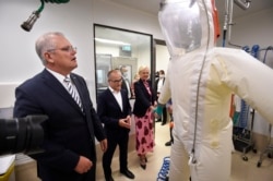 Le Premier ministre australien Scott Morrison, à gauche, regarde une combinaison à risque lors d'une visite dans une structure de santé à Melbourne, mardi 14 décembre 2021.