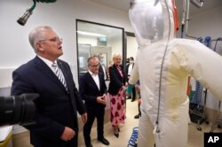 Le Premier ministre australien Scott Morrison, à gauche, regarde une combinaison à risque lors d'une visite dans une structure de santé à Melbourne, mardi 14 décembre 2021.