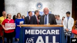 FILE - Sen. Bernie Sanders, I-Vt., is joined by Democratic Senators and supporters as he arrives for a news conference on Capitol Hill in Washington, Sept. 13, 2017.