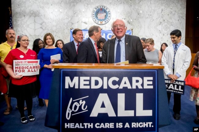 FILE - Sen. Bernie Sanders, I-Vt., is joined by Democratic Senators and supporters as he arrives for a news conference on Capitol Hill in Washington, Sept. 13, 2017.