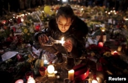 A girl lights candles as people pay tribute to the victims of Tuesday's bomb attacks, at the Place de la Bourse in Brussels, Belgium, March 26, 2016.