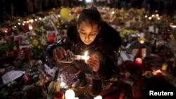 یک دختر جوان برای قربانیان حملات بروکسل شمع روشن می کند. 