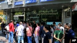 People line up in front of a currency exchange shop to buy U.S. dollars and euros, in downtown Tehran, Iran, Sept. 5, 2018. The Iranian rial fell Wednesday to its lowest rate on record and saw worried residents of Tehran line up outside of beleaguered mon