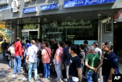 People line up in front of a currency exchange shop to buy U.S. dollars and euros, in downtown Tehran, Iran, Sept. 5, 2018.