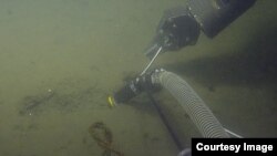 A suction hose is used to collect sediment samples from the ocean floor during work by the team aboard the Nautilus, in the search for meteorite pieces in the ocean. (NautilusLive.org)