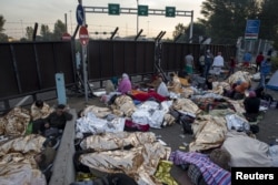 Migrants sleep on a highway in front of a barrier at the border with Hungary near the village of Horgos, Serbia, Sept. 16, 2015.