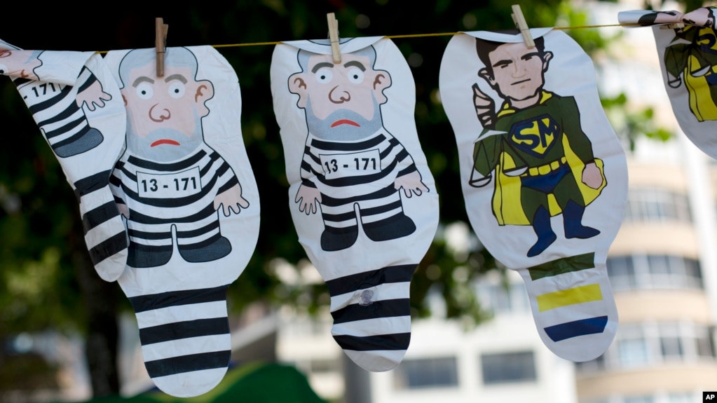 FILE - A set of inflatable dolls in the likeness of former President Luis Inacio Lula da Silva in prison garb and Judge Sergio Moro as a superhero hang on a line during a protest against corruption and in support of the Car Wash investigation in Rio de Janeiro, March 26, 2017. 