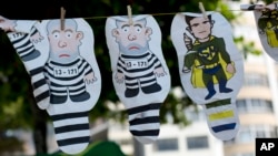 FILE - A set of inflatable dolls in the likeness of former President Luis Inacio Lula da Silva in prison garb and Judge Sergio Moro as a superhero hang on a line for sale during a protest against corruption and in support of the Car Wash investigation on Copacabana beach, in Rio de Janeiro, Brazil.