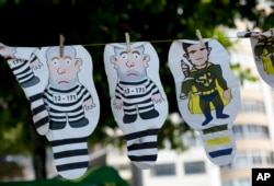 FILE - A set of inflatable dolls in the likeness of former President Luis Inacio Lula da Silva in prison garb and Judge Sergio Moro as a superhero hang on a line for sale during a protest against corruption and in support of the Car Wash investigation on Copacabana beach, in Rio de Janeiro, Brazil, March 26, 2017.